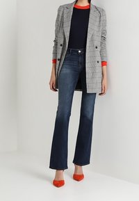 Szary marynarka w kratę z czerwonymi akcentami, granatowa bluzka, ciemnoniebieskie dzwony i pomarańczowe szpilki. Skoncentruj się na dopasowanym kroju i kontrastowych kolorach.