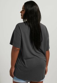 Oversized gray cotton t-shirt with short sleeves, a rounded hem, and a relaxed fit, paired with light blue denim shorts.