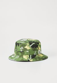 Zelena kapa s širokim obodom i cvjetnim uzorkom u crnoj i žutoj boji, izrađena od pamuka, sa šivenim detaljima.