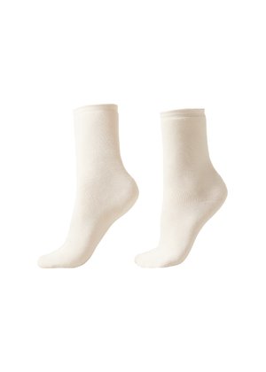 Par de calcetines tobilleros lisos de color blanco hueso, mostrados uno al lado del otro, mostrando cobertura del pie y del tobillo con bordes de puño acanalados.