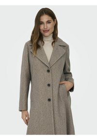 Manteau en laine brun clair avec de grands revers en pointe, fermeture à boutons sur le devant et poches latérales. Texture lisse, coupe ajustée et design à un bouton.