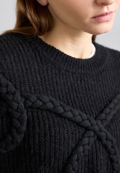 Schwarzer gestrickter Pullover mit strukturiertem Finish und geflochtenen Mustern auf der Brust. Rippkragen und -bündchen sorgen für eine formende Struktur.
