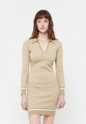 Abito lavorato a maglia in beige con motivo a rombi bianchi, scollatura a V e colletto. Maniche lunghe e orli a costine caratterizzano il design.