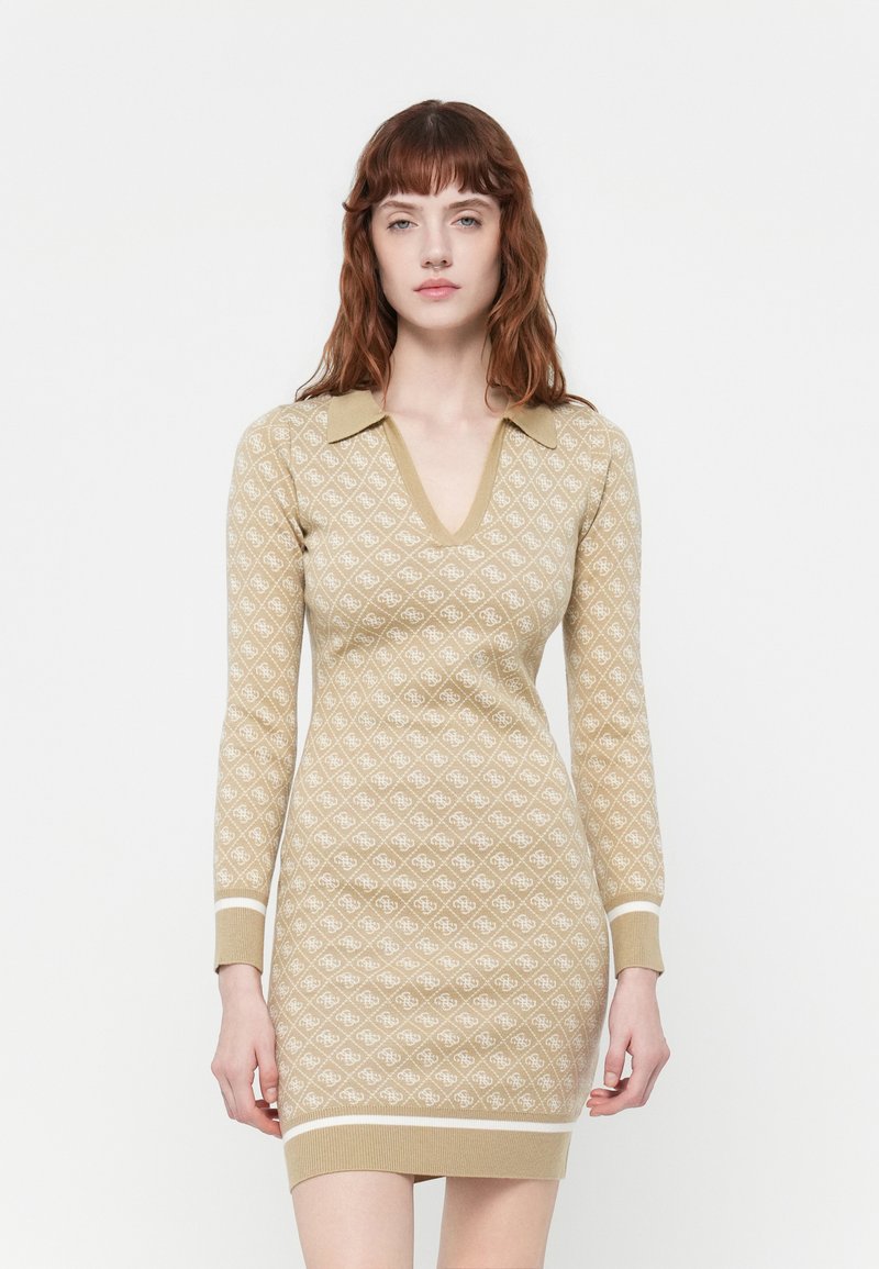 Rochie tricotată în bej cu un model alb în diamant, cu decolteu în V și guler. Mâneci lungi și tivuri ribbate completează designul.