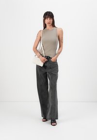 Grå ribbet ermeløs topp, svarte vide jeans og svarte åpne tå hæler. En liten hvit quiltet crossover-veske gir detaljer.