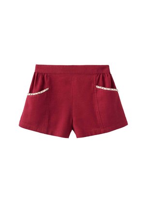 Short rouge à taille haute et poches latérales ornées de dentelle florale blanche sur fond blanc.