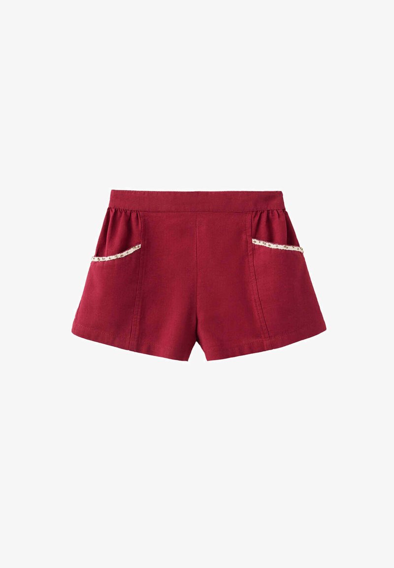 Short rouge à taille haute et poches latérales ornées de dentelle florale blanche sur fond blanc.