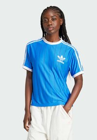 Camiseta deportiva azul con rayas verticales, cuello y puños en blanco, con el logo de Adidas en blanco en el pecho. Material ligero.