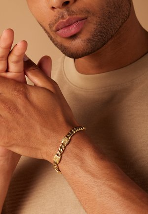 Gold chain bracelet with textured square accents, featuring a sleek, interlinked design. Smooth surface and warm metallic shine.