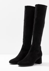 Schwarze Wildlederstiefel in kniehoher Form mit Blockabsatz, spitzer Zehenform und nahtlosem Design; zeichnet sich durch eine weiche Textur und einen minimalistischen Stil aus.