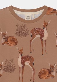 T-shirt in cotone marrone con varie illustrazioni di cervi maculati e erba in un motivo ripetuto, con design a girocollo.