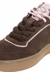 Närbild av brun mockaskor med tjock strukturerad beige sula, ljusrosa foder och tunga med rosa- och svartspräckligt mönster samt matchande snören.