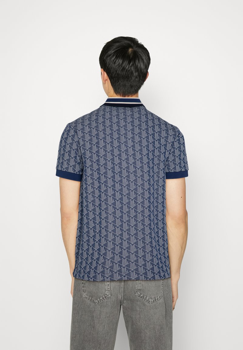 Navy polo shirt met een patroon, voorzien van een kraag en korte mouwen. Gemaakt van textuurstof, met contrasterende accenten op de kraag en mouwen.
