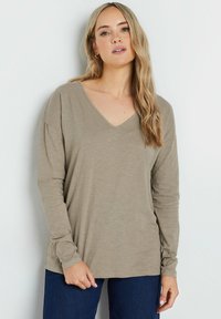 Langsleeve, V-hals top van zachte taupe stof met een relaxte pasvorm, voorzien van een soepele textuur en subtiele stiksels. Draagt het met donkere jeans.