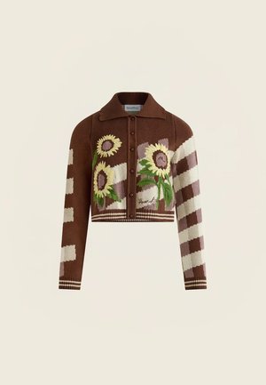 Hnědý krátký kardigan se slunečnicovými vzory, zapínáním na knoflíky vpředu, límcem a krémovými a fialovými kostkovanými rukávy.