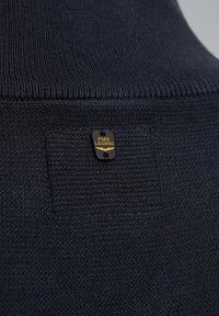 Maglione lavorato a maglia blu navy con scollatura a costine, dotato di un'etichetta nera con la scritta "PME LEGEND" stampata in giallo. Dettaglio del tessuto testurizzato visibile.