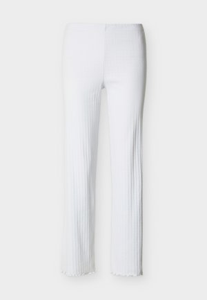 Balti riboti taisnā stila bikses ar augsto jostasvietu un nelielu volānu detaļu apakšmalā, attēlotas uz gaiša fona.