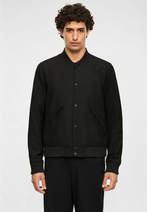 Sort bomberjakke med ribbet krave, knapper foran og sidelommer. Fremstillet af et glat stof med en tætsiddende silhuet.
