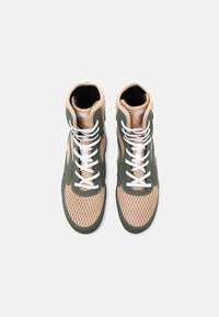 Πλατφόρμες με μπεζ υφαντό ύφασμα και πράσινες επενδύσεις, λευκά κορδόνια και θηλιές τράβηγματος, εμφανιζόμενες σε άποψη από πάνω σε λευκό φόντο.