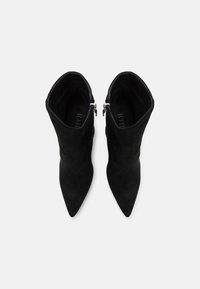 Bottines en daim noir avec un bout pointu, fermeture éclair sur le côté et une texture lisse. Le design présente une silhouette ajustée.