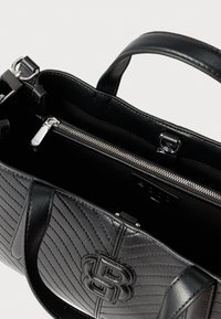 Czarna skórzana torebka z pikowanym wzorem, srebrnymi okuciami, zamknięciem na górny zamek i dwoma uchwytami. Wnętrze wyposażone w kieszeń na zamek dla bezpiecznego przechowywania.