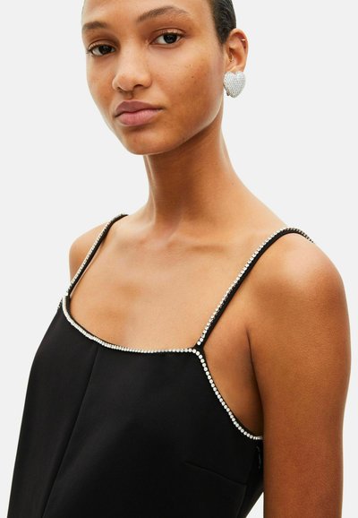 Camisole en satin noir avec fines bretelles, ornée d'accents en cristal le long du décolleté et d'un design minimaliste. Texture lisse, look élégant.