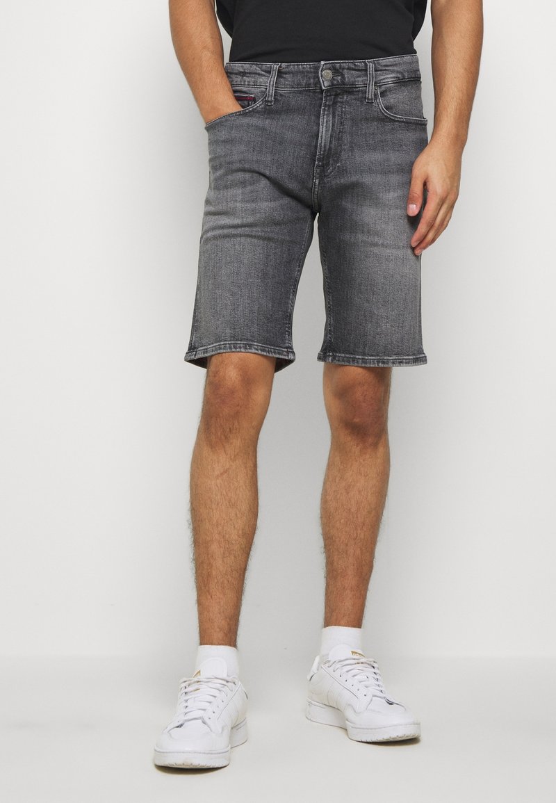 Shorts in denim grigio con vestibilità regolare, design a cinque tasche e orli arrotolati, abbinati a sneaker bianche. Texture liscia con minima scoloritura.