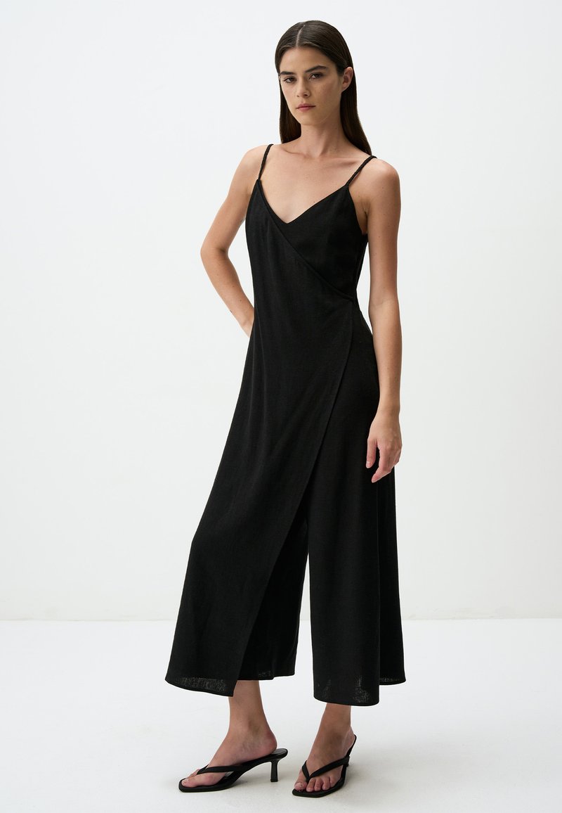 Zwarte mouwloze jumpsuit met een V-hals, wikkeldesign en brede pijpen. Gemaakt van lichtgewicht stof, met dunne bandjes en een lengte tot halverwege de kuit.
