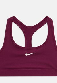 Sostenedor deportivo púrpura de Nike con diseño de espalda cruzada y logo de swoosh de Nike en blanco centrado en la parte delantera.