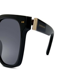 Černé oversized sluneční brýle s tmavými skly, s lesklým povrchem. Výrazné zlaté detaily a branding na straně.