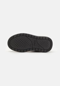 Black rubber shoe sole with textured grip pattern, featuring small ventilation holes and a segmented design for flexibility.