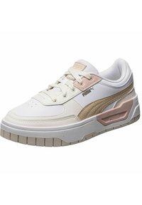 Puma sporta apavi baltā un gaiši rozā krāsā, ar ādas un teksturēta tīklveida augšdaļu, biezu gumijas zoli un izteiktu logo sānos.