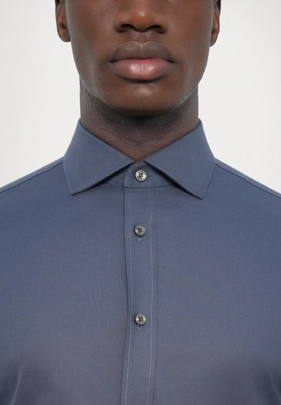 Chemise à manches courtes, de couleur gris foncé, avec un col pointu, deux boutons sur le devant et une texture subtile. Fini en tissu lisse.
