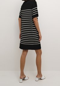 Sukienka w biało-czarne paski z krótkimi rękawami, luźny krój, długość do kolan, górna część w jednolitym czarnym kolorze, teksturowana tkanina i prosty dół.