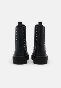 Black leather ankle boots with silver studs along the sides, a pull tab at the back, and a thick black sole for added height.