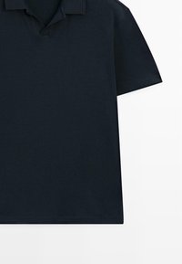 Polo à manches courtes de couleur bleu marine foncé uni, avec col plié et patte de boutonnage, présenté à plat sur un fond blanc.