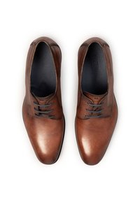 Paire de chaussures formelles en cuir marron poli avec des lacets noirs, vue du dessus sur un fond blanc.