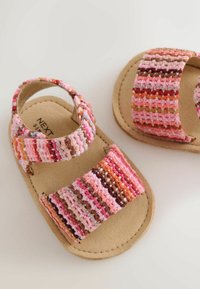 Sandales bébé à semelle souple avec lanières tissées réglables roses, marron et orange sur des semelles beiges, conçues pour les nourrissons de 0 à 3 mois.