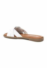 Chanclas blancas con un diseño de tiras trenzadas, que cuentan con una suela de goma plana en tono marrón y un acabado suave en el material superior.