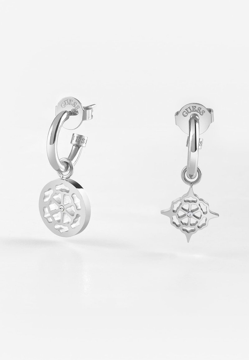 Silberne Creolen mit aufwendigen Ausschnittdesigns. Eine hat einen runden Anhänger; die andere einen sternförmigen Anhänger mit einem kleinen Stein.
