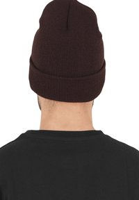 Brown knit beanie with a rolled cuff, made of soft material, featuring a simple design and smooth texture, viewed from the back.