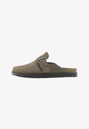 Brązowy zamszowy chodak wsuwany z regulowanym paskiem i metalową klamrą, czarną protektorem na podeszwie oraz korkowym wkładką widoczną przy pięcie.