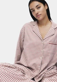 Ensemble de pyjama à carreaux rose et crème, composé d'un haut à boutons avec col et poche, associé à un bas de pyjama ample.