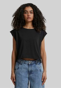 T-shirt noir court avec des manches courtes, fabriqué en coton doux. Associé à un jean taille haute bleu clair avec des détails déchirés.