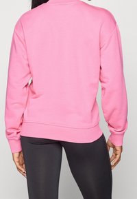 Sweat-shirt rose à manches longues et encolure ronde, fabriqué en matériau doux, avec ourlet et poignets côtelés.