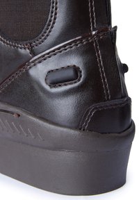 Bota de cuero marrón con una textura suave, costuras reforzadas, acentos negros y una suela de goma ligeramente elevada con surcos para tracción.