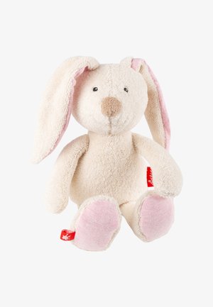 Lapin en peluche doux couleur crème avec de longues oreilles bordées de rose, des coussinets roses et une petite étiquette en tissu rouge sur le côté gauche.