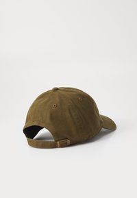 Brun justerbar baseballcaps med stoffrem og metallspenne på hvit bakgrunn, vinkelrett for å vise baksiden og siden.
