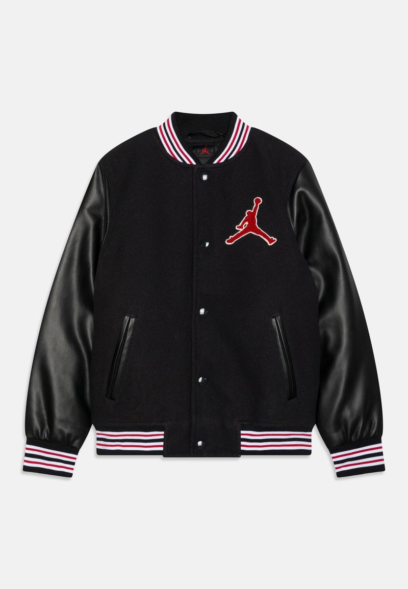Černá varsity bunda s černými koženými rukávy, červenými a bílými pruhovanými manžetami a červeným vyšívaným logem Jumpman na hrudi. Obsahuje patentky a boční kapsy.