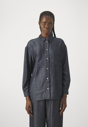 Camicia in denim blu scuro con botttoni, caratterizzata da maniche lunghe, due tasche sul petto e bottoni in argento lucido, con una finitura in tessuto testurizzato.